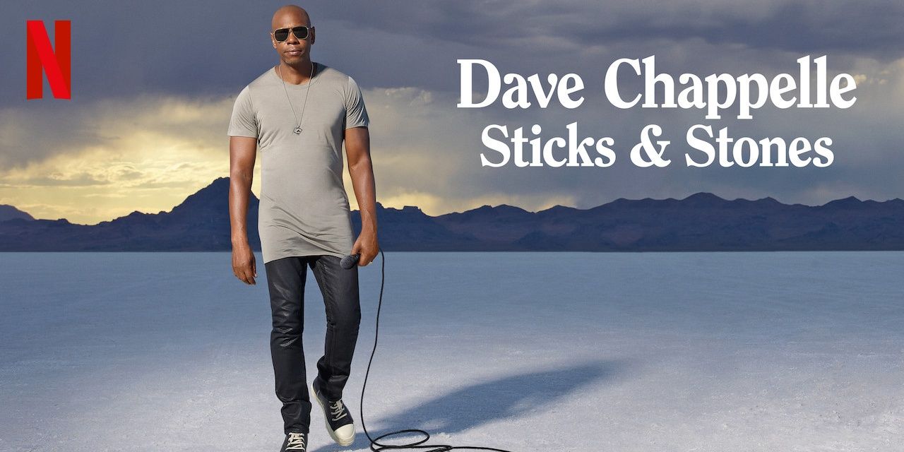 Dave Chappelle holding a microphone on a piece of art for Sticks & Stones.